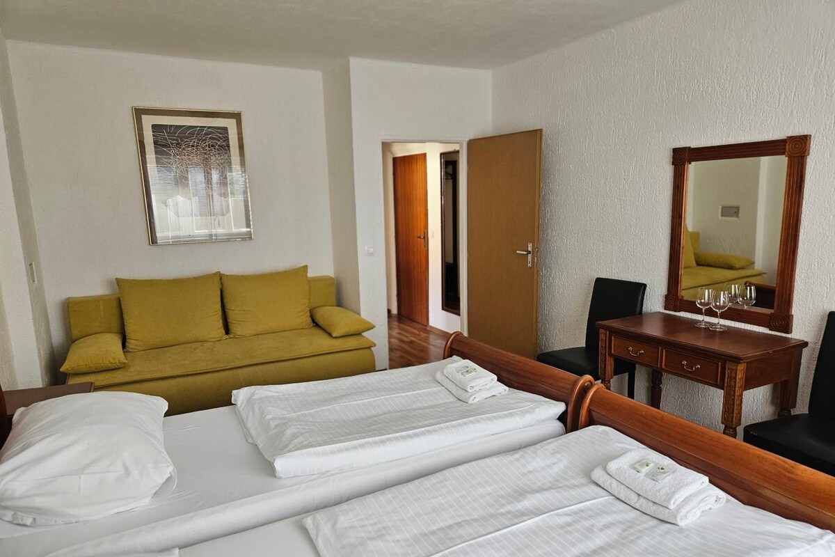 Una habitación de hotel con cama, sofá, escritorio y espejo.