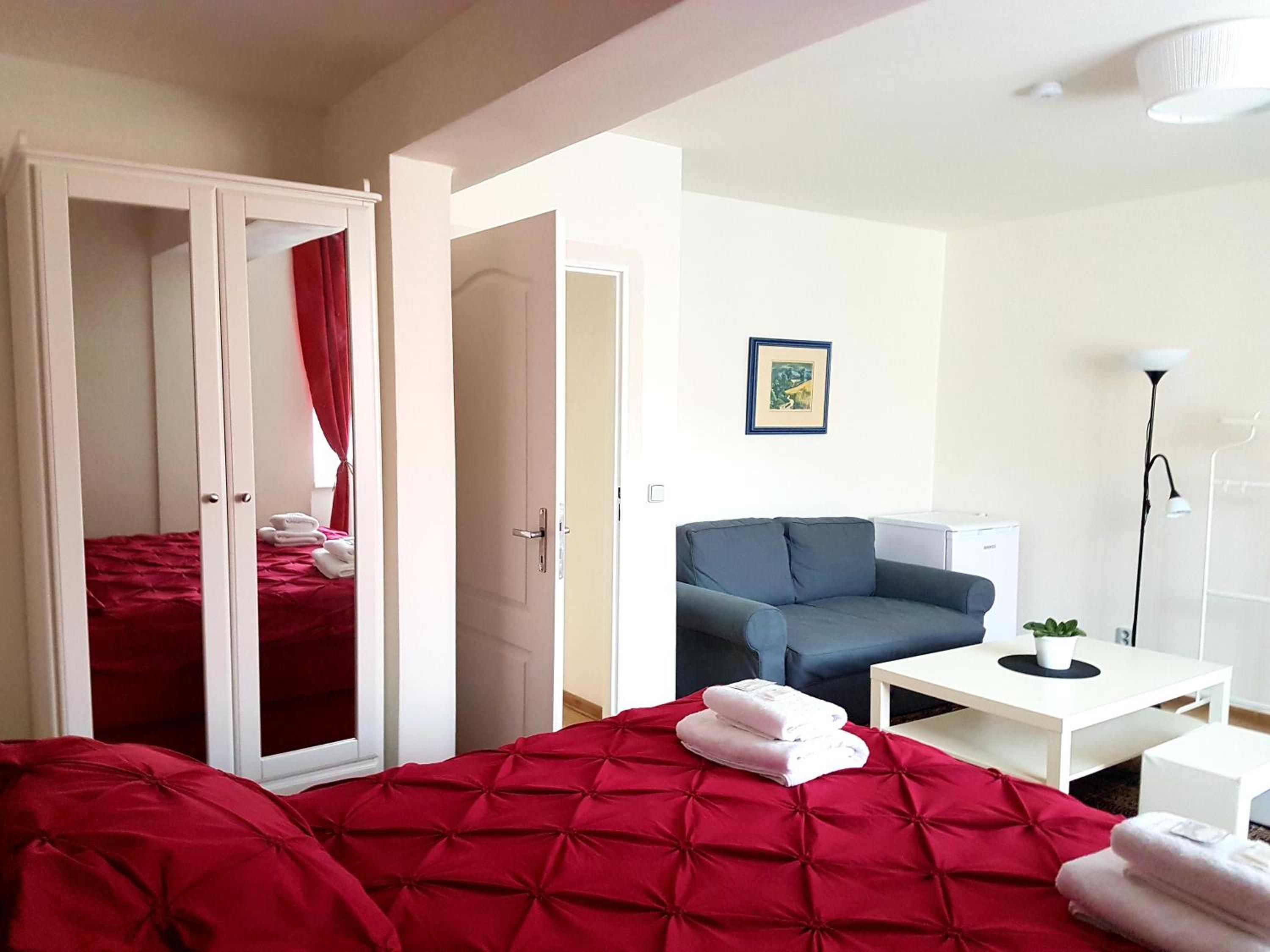 A hotel room with a bed, a sofa, a desk, and a wardrobe.