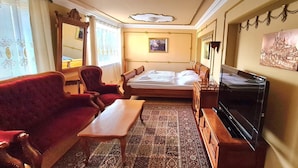 Una habitación de hotel con cama, televisor, sofá, mesa y alfombra.