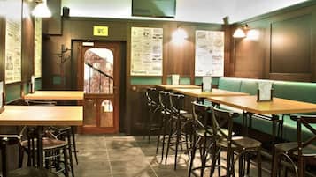 A restaurant interior with wooden tables and chairs, a green booth, and menu boards on the walls.