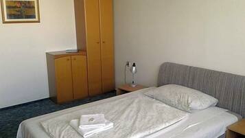 A hotel room with a bed, a wardrobe, a nightstand, and a lamp.