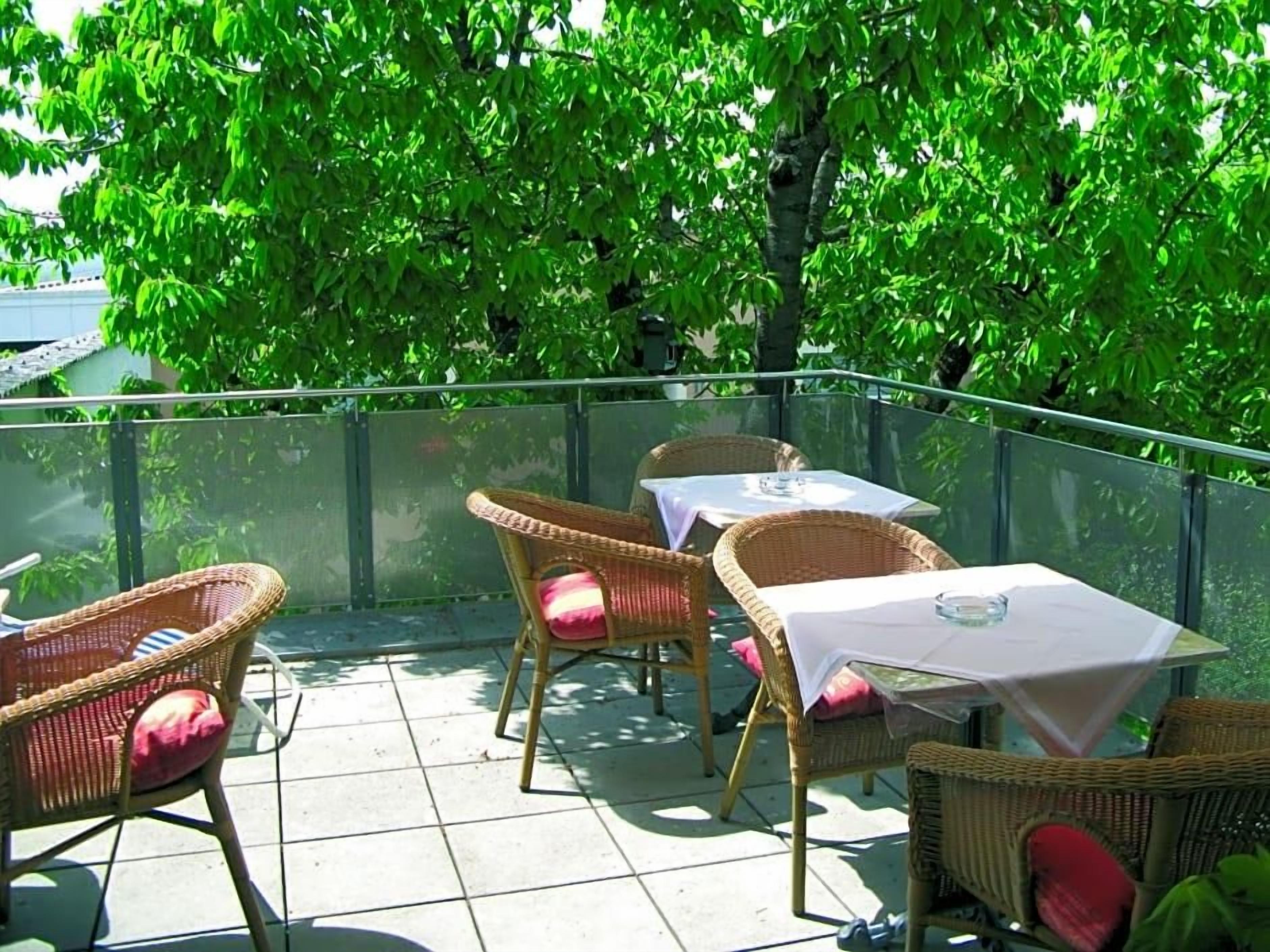 Une terrasse extérieure aménagée avec des meubles en osier et une table, le tout entouré de verdure.