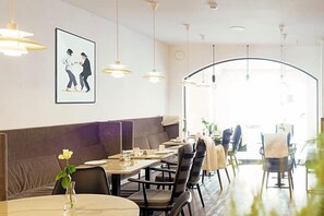 A restaurant with booths, tables, and hanging pendant lights. - Altstadthotel Wetzel (Mühldorf am Inn)