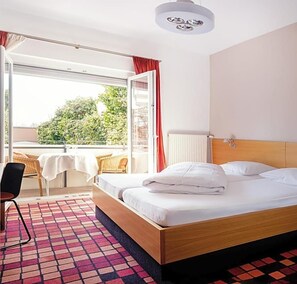 Een hotelkamer met een bed, een stoel, een tafel en uitzicht op groen.