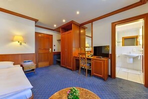 A hotel room with a bed, desk, chair, television, and a bathroom. - Hotel Fischerwirt (Ismaning)