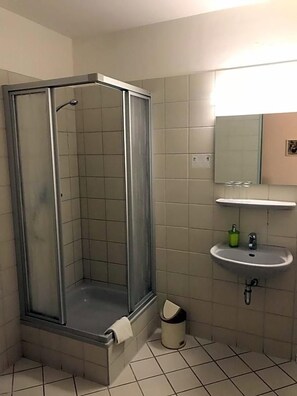 Un baño con cabina de ducha, lavamanos y espejo.