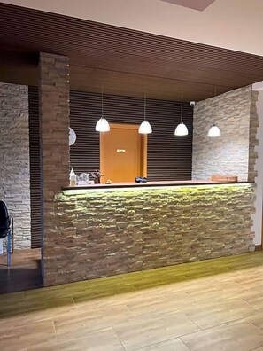 Un área de recepción con pared de piedra, techo de madera e iluminación colgante.