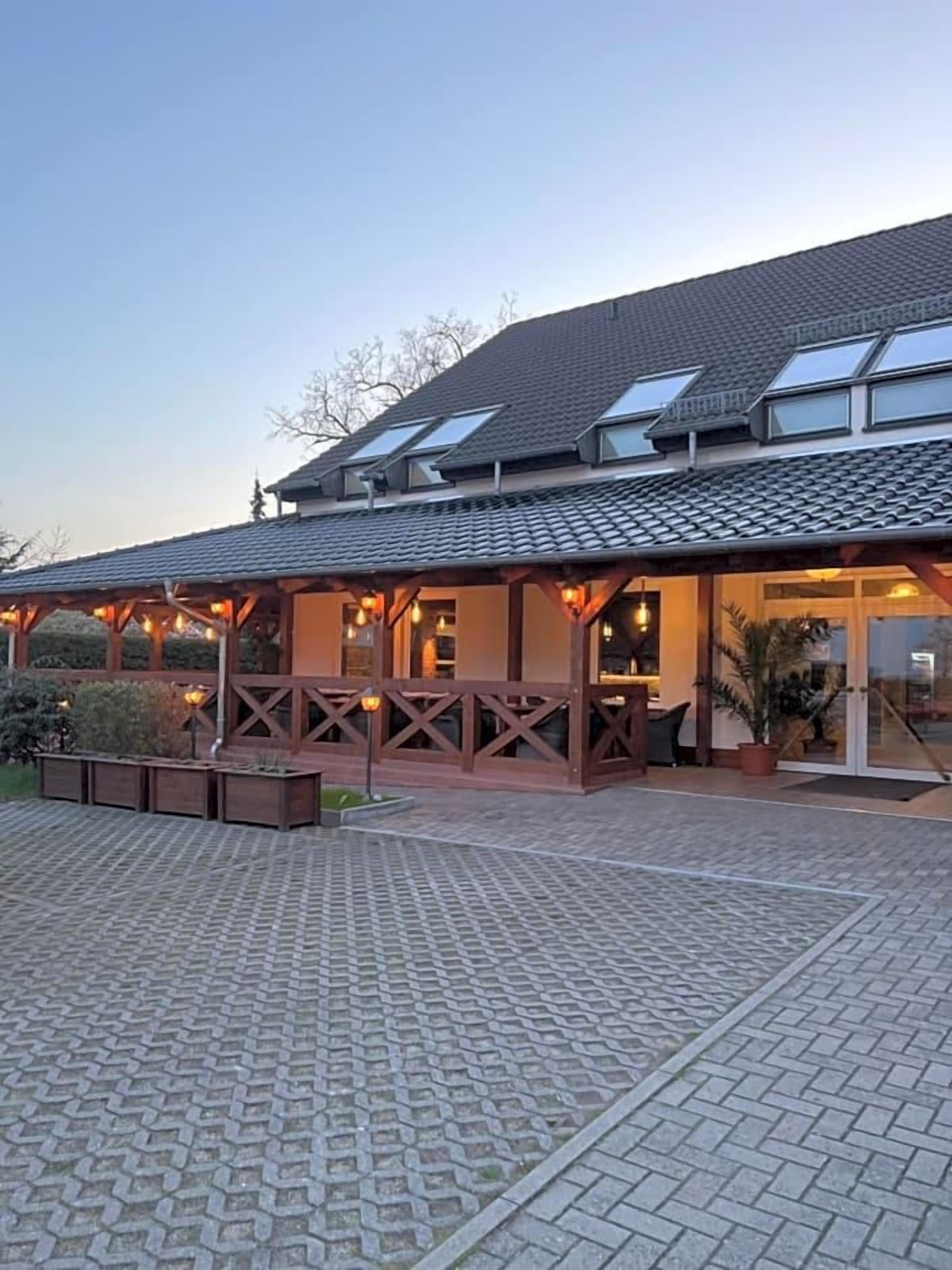 Ein Gebäude mit überdachter Terrasse, gefliestem Eingangsbereich und einem Dach mit Oberlichtern.