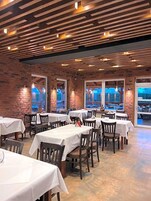 Un restaurante con paredes de ladrillo, vigas de madera en el techo y mesas dispuestas para comer.