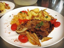 Un plato con filete, papas y tomates cherry.