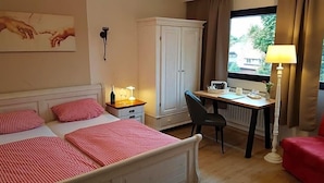 A hotel room with a bed, a desk, a chair, a wardrobe, and a window with curtains. - Landhotel Restaurant Beckmann (Heiden)