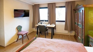A hotel room with a bed, a desk, a chair, a television, and a window with curtains. - Landhotel Restaurant Beckmann (Heiden)