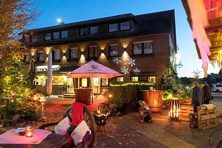 A building with a brick facade, outdoor seating area with tables and chairs, and a red umbrella.