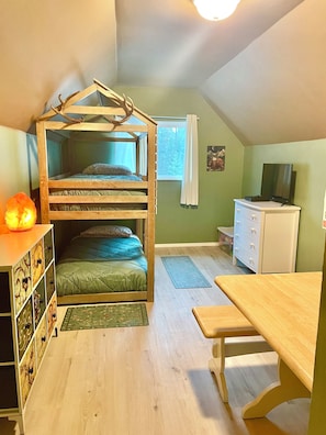 Una habitación con una cama litera, un escritorio, un aparador, un televisor y una ventana con cortinas.
