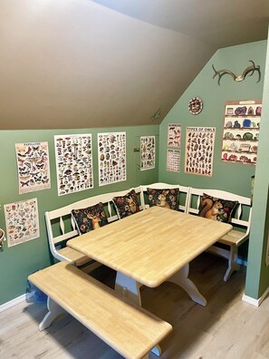 Un comedor con una mesa de madera y bancos, rodeado de carteles educativos sobre fauna y minerales.