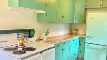 Una cocina con armarios color turquesa, una estufa blanca y un refrigerador blanco.