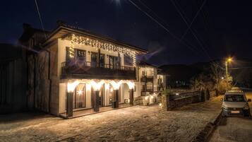 A two-story building with a balcony, stone flooring, and string lights.