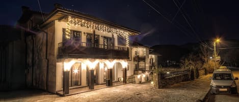 A two-story building with a balcony, stone flooring, and string lights.