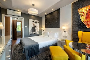 A modern hotel room with a bed, bedside tables, a yellow armchair, and a large abstract painting. - Family Hotel Strannopriemnitza (Troyan)