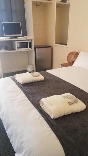 A hotel room with a bed, a desk with a computer and a microwave, a refrigerator, and a mirror. - Wimmera Motel (Nhill)