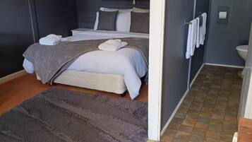 A compact room with a bed, a small bedside table, a radiator, and a view of the outside.