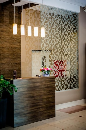 A reception desk with a wooden finish, a patterned wall, and hanging pendant lights.
