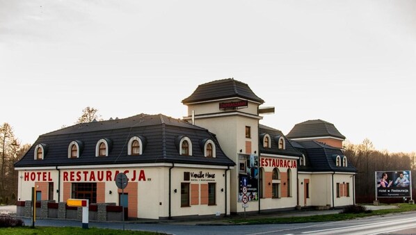 A building with signs for a hotel and restaurant, a sign for a vanilla house, and a sign for a restaurant.