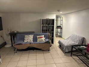 A living room with a sofa, a table, a fan, and a shelving unit. - 1 bedroom w/yard Einstein Hospital (Philadelphia)