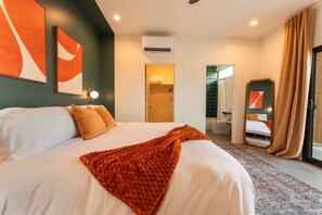 A hotel room with a large bed, a bathroom visible through an open door, and a view of the outside. - Hōkū Hale | Spa | Sauna | Fire Pit | 360° Views (Joshua Tree)