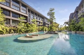 Un hôtel doté d’une piscine, entouré d’une végétation luxuriante et de bâtiments modernes.
