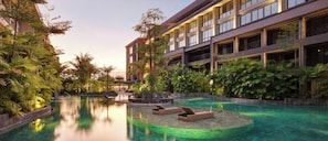 A hotel with a pool area, lounge chairs, and lush greenery.