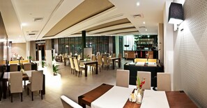 Un restaurante moderno con varias zonas de comedor, incluyendo una zona de bar y lounge con barra y asientos.