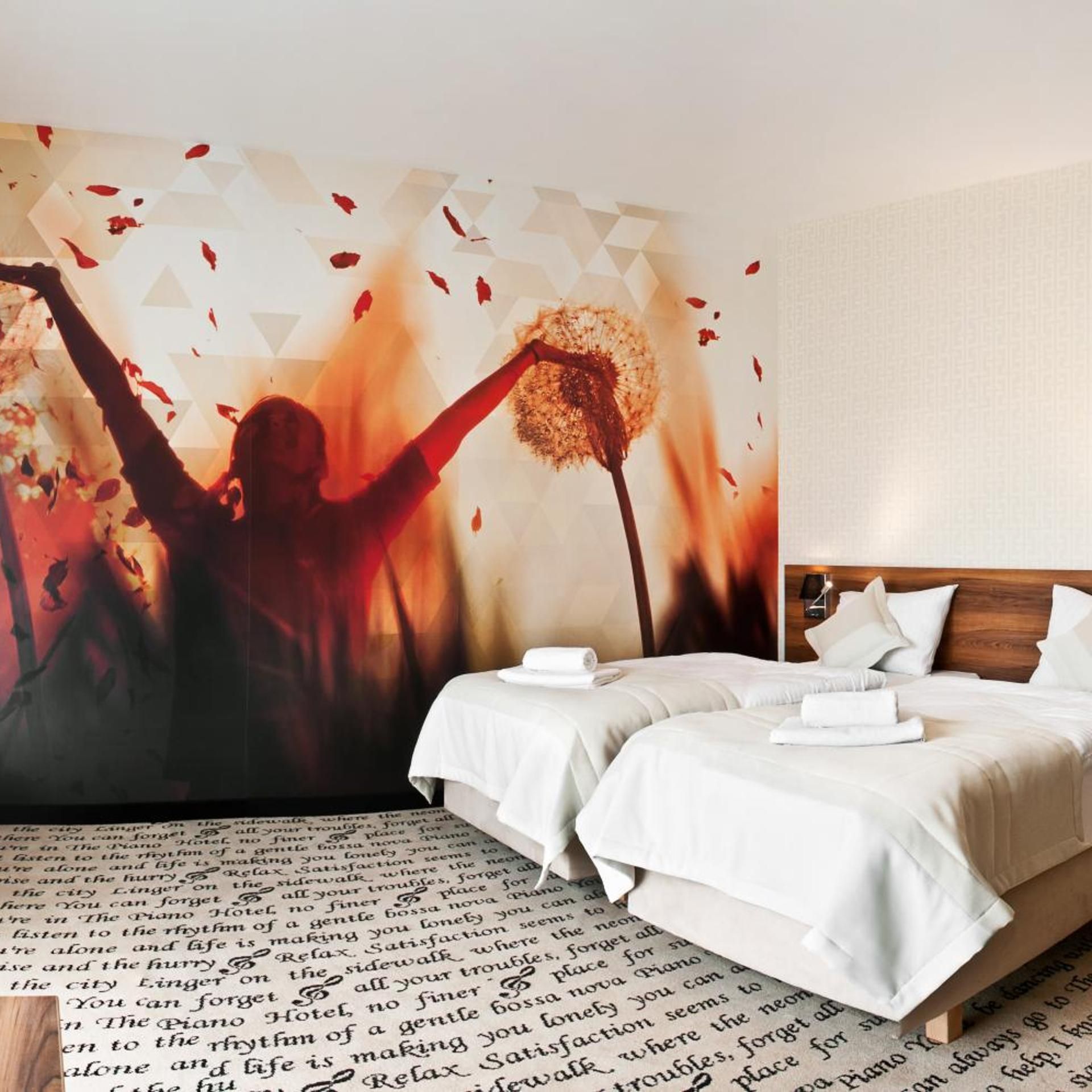 Ein Hotelzimmer mit einer großen Wandmalerei, zwei Betten mit weißer Bettwäsche und einem hölzernen Kopfteil.