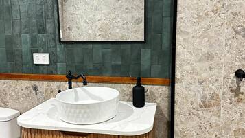 A bathroom with a wooden vanity, a white sink, and a mirror.