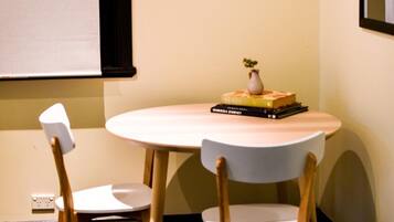A small, round table with two chairs, a vase with a plant, and a stack of books.