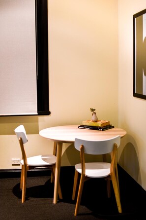 A small, round table with two chairs, a vase with a plant, and a stack of books.
