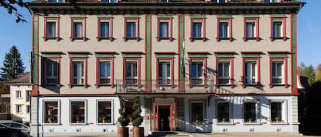 A multi-story hotel with a symmetrical facade, large windows, and a central entrance with a red door.