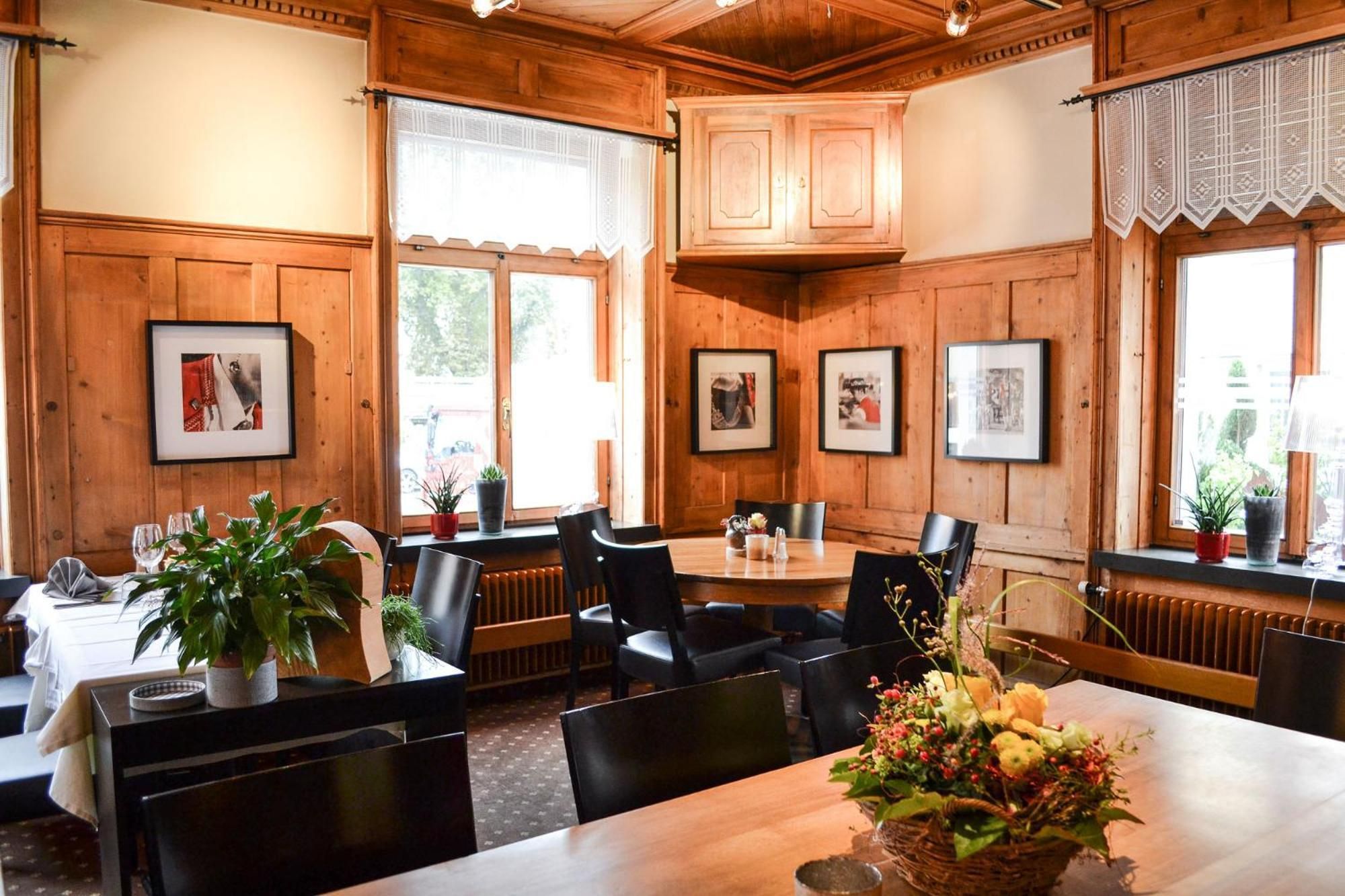 A restaurant with wooden paneling, framed pictures on the walls, and a table set for dining.
