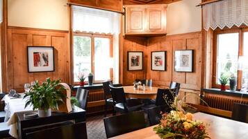 A restaurant with wooden paneling, framed pictures on the walls, and a table set for dining.