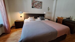 Habitación de hotel con una cama grande, dos mesitas de noche, una lámpara de pared, un cuadro y una silla.