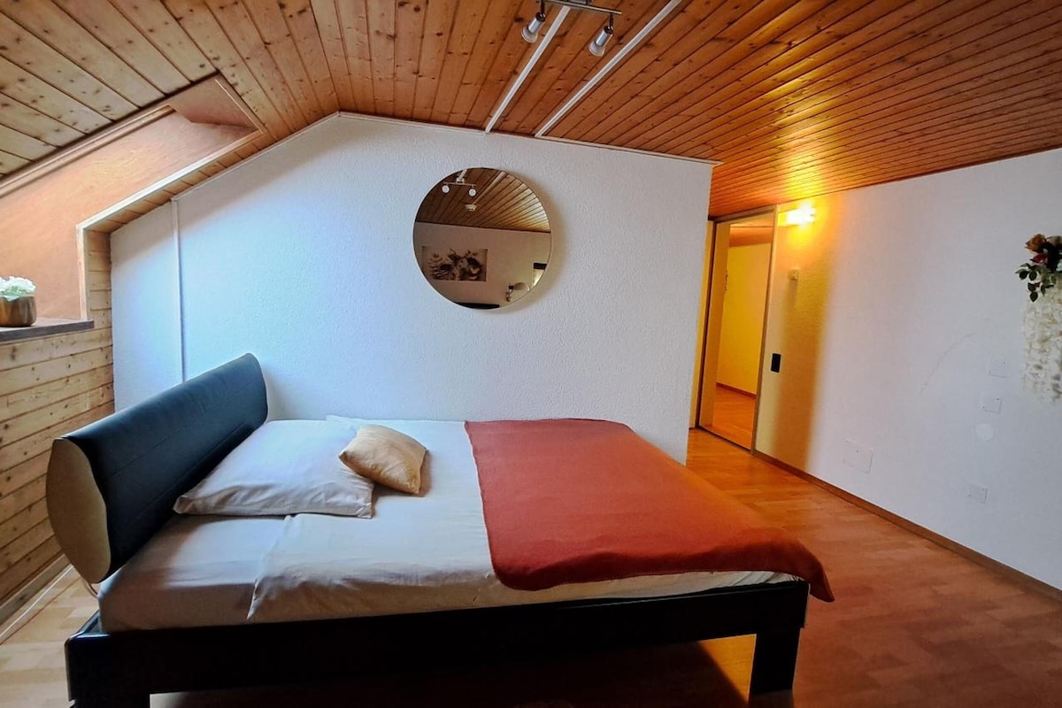 A bedroom with a bed, a mirror, and a wooden ceiling.