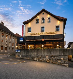 Un hôtel avec une enseigne indiquant « Hôtel de la Fontaine » et une entrée bien visible.