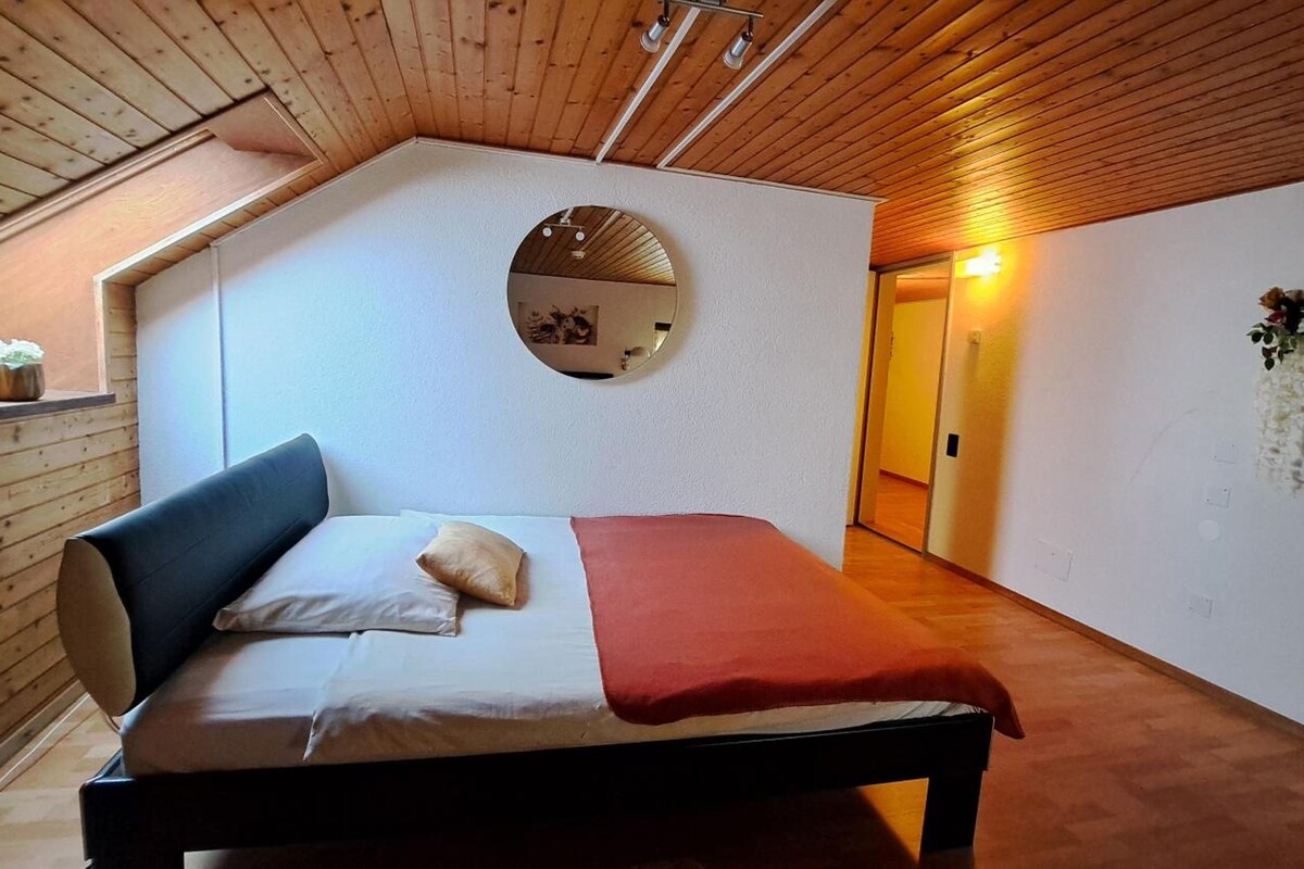A bedroom with a bed, a mirror, and a wooden ceiling.
