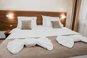 A hotel room with a wooden headboard, white bedding, and two pillows. - Hotel Damis (East Sarajevo)