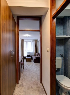 A hallway leading to a living area with a sofa, a coffee table, and a dining table. - Hotel Damis (East Sarajevo)