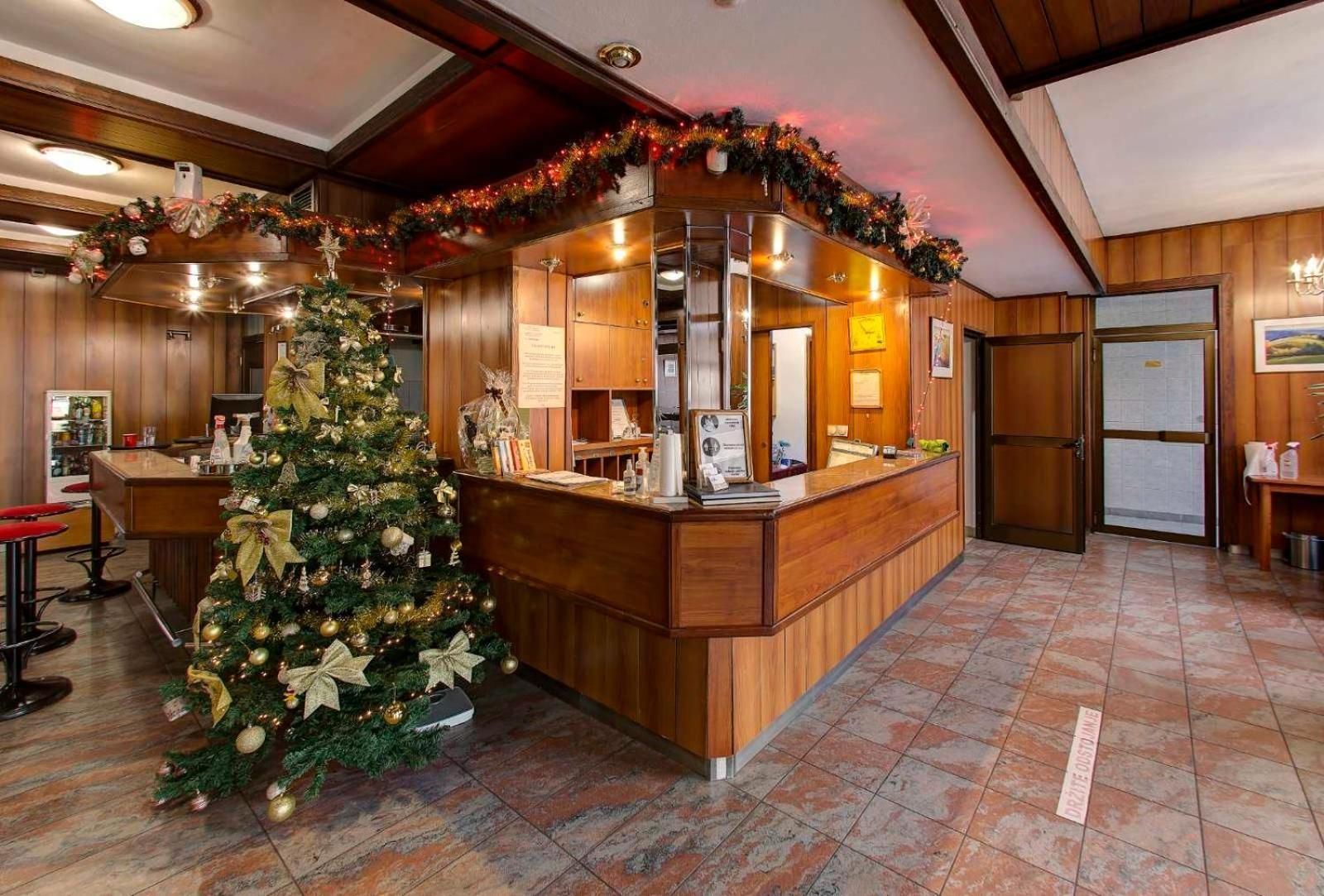 Zona de recepción con mostrador de madera, un árbol de Navidad y piso de baldosas.