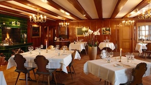 A restaurant with multiple tables set for dining, wooden paneling, chandeliers, and a fireplace. - Landgasthof Hotel Rv Ssli (Adligenswil)