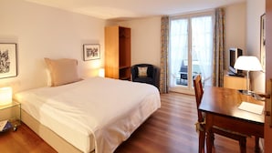 A hotel room with a bed, a desk, a chair, a wardrobe, and a window with curtains. - Landgasthof Hotel Rv Ssli (Adligenswil)