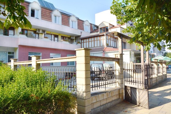 A residential building with multiple balconies, a gated entrance, and a paved pathway. - Hotel Wesso (Kavarna)
