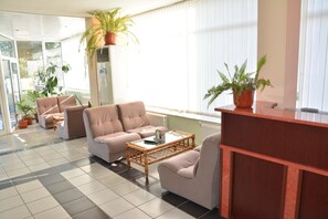 A modern living room with a sofa set, a coffee table, and a reception desk. - Hotel Wesso (Kavarna)